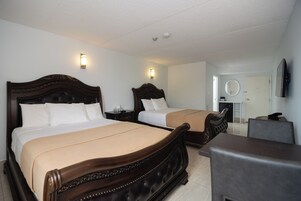 Habitación de hotel con dos camas, un escritorio, una silla, un televisor y un espejo.