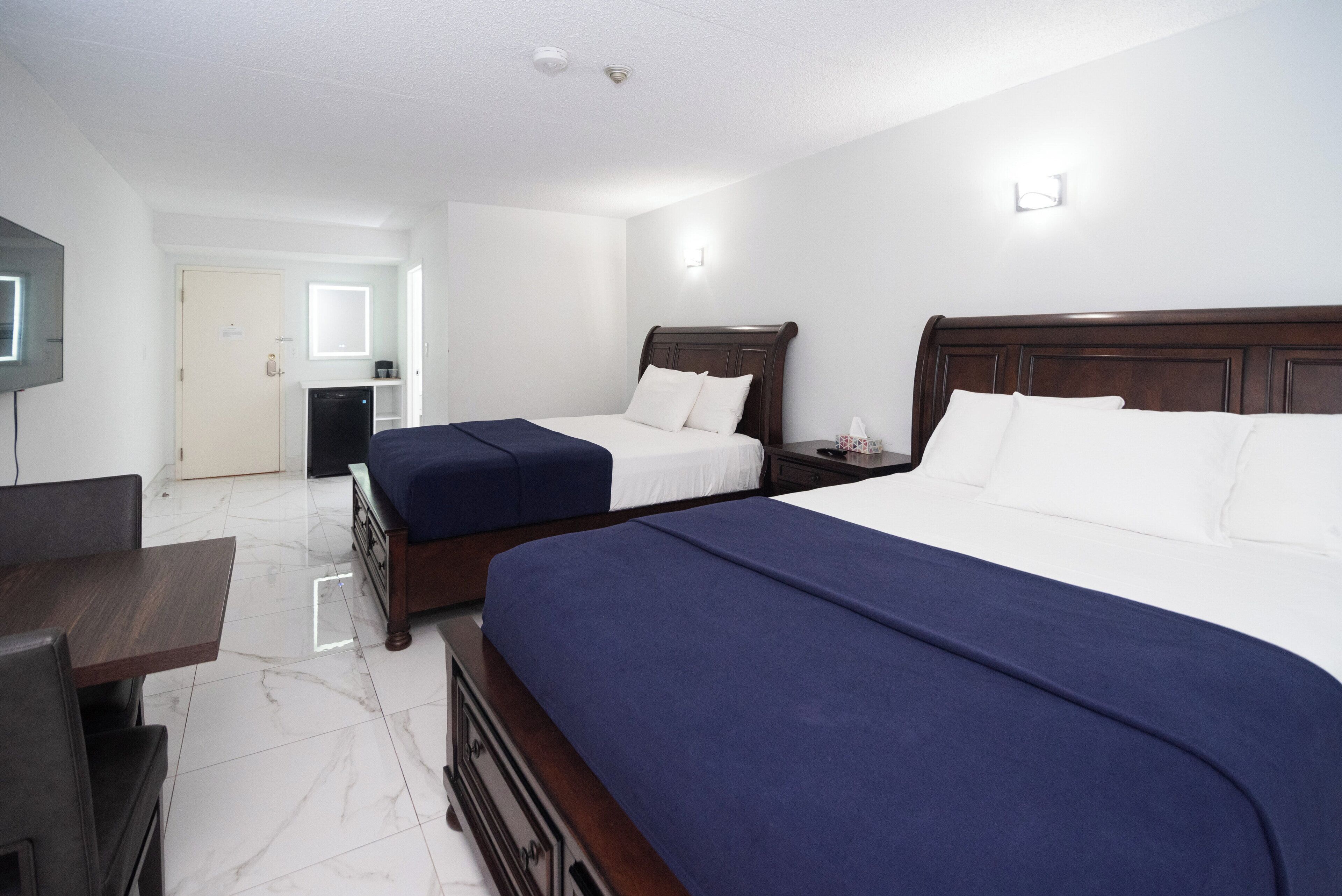 Une chambre d’hôtel avec deux lits, un bureau et une télévision.