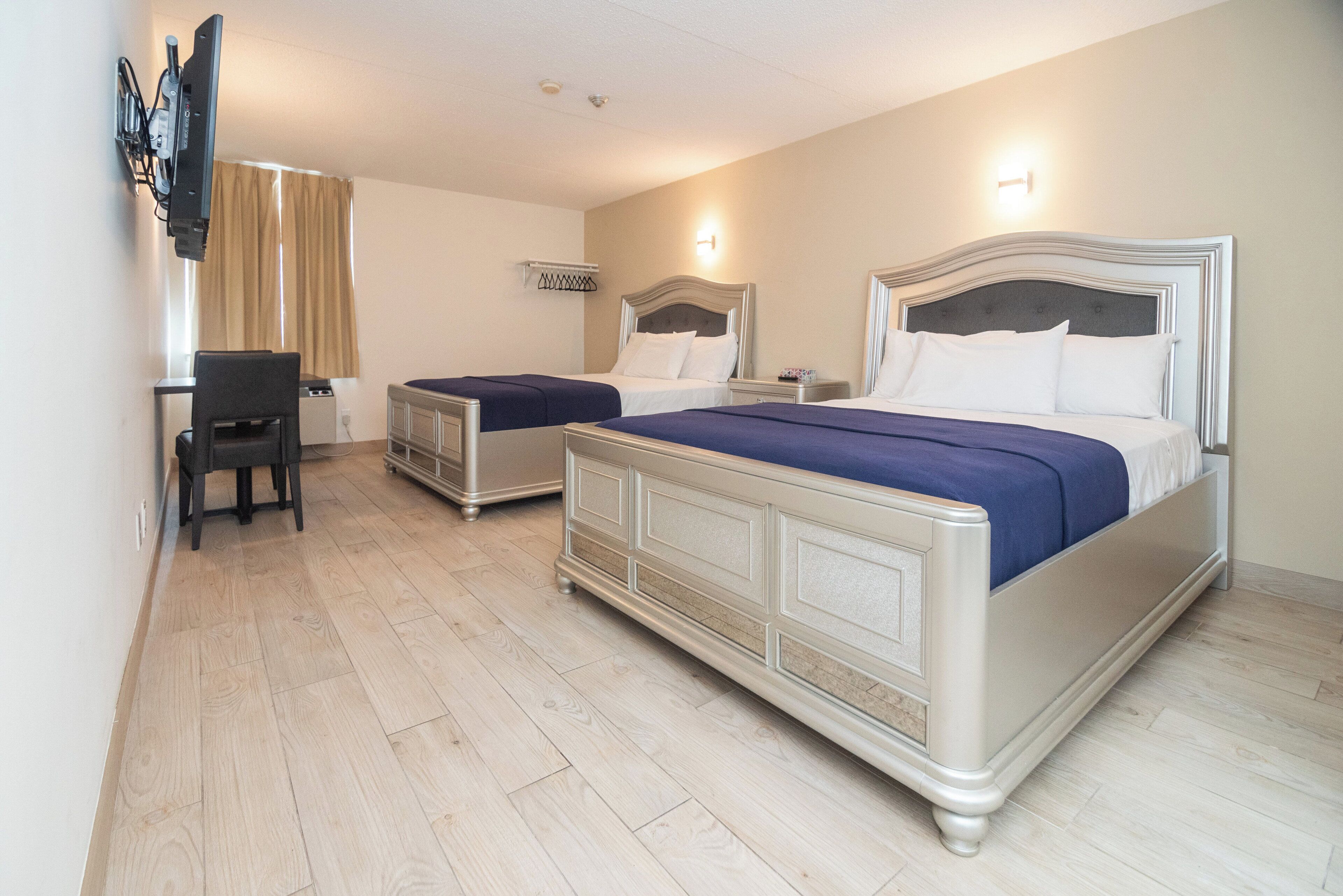 Une chambre d’hôtel avec deux lits, un bureau et une chaise.