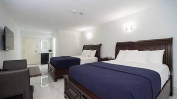 A hotel room with two beds, a TV, a desk, and a mirror.