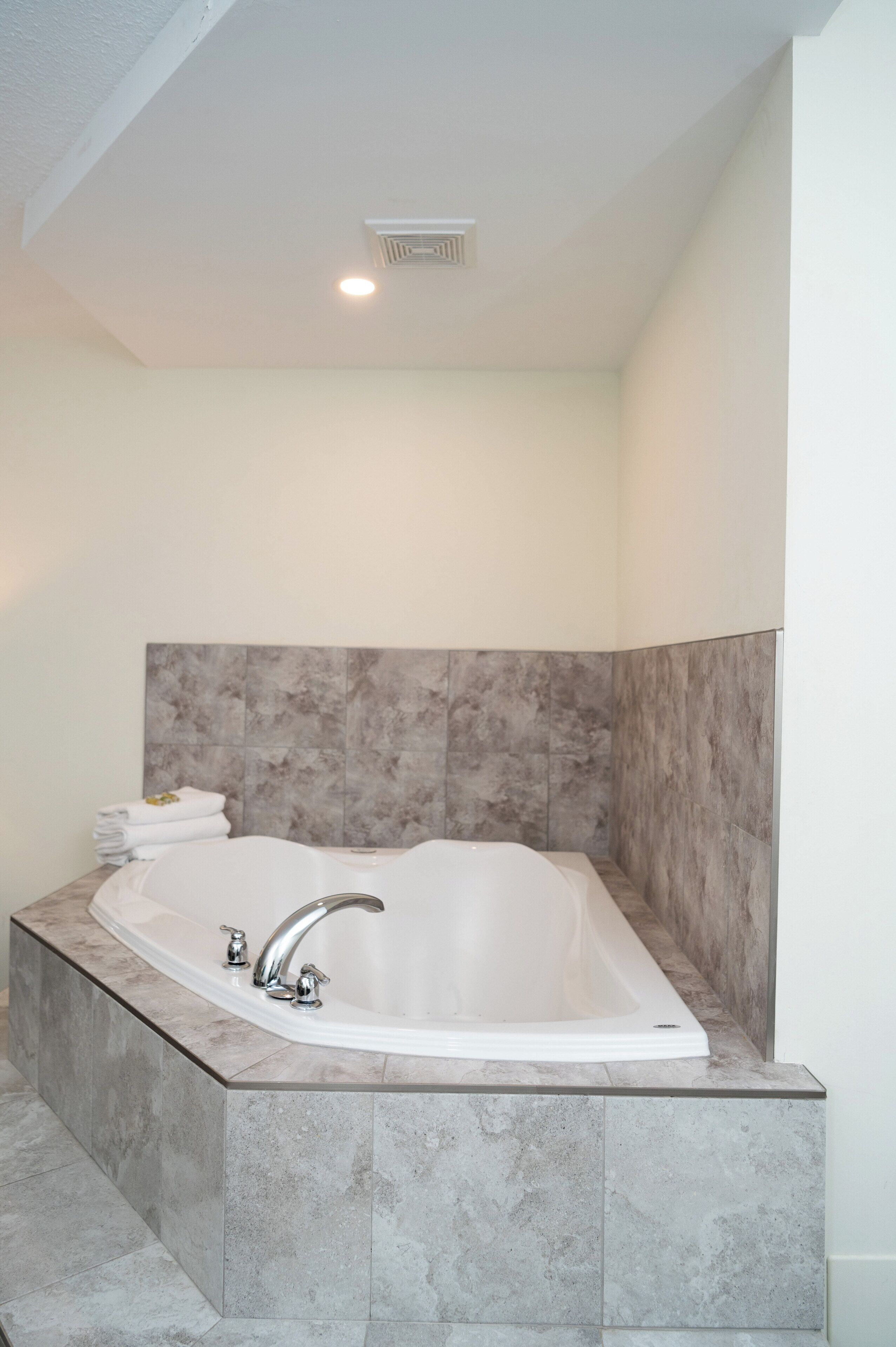 A modern bathroom with a freestanding bathtub, marble tiles, and a towel stack.