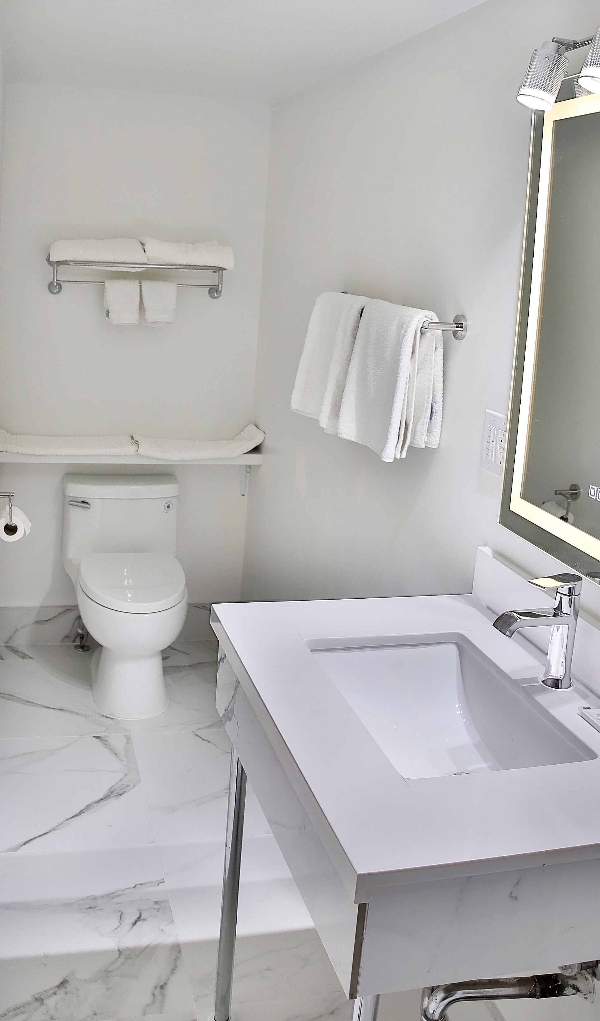 Un bagno moderno con lavandino, water e portasciugamani bianchi.