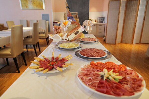 Una mesa de bufé con diversos alimentos, incluyendo carnes, quesos y pan.