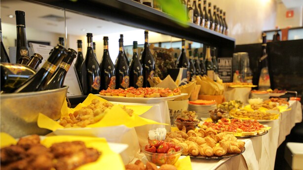 Una mesa de buffet con diferentes alimentos y botellas de vino.
