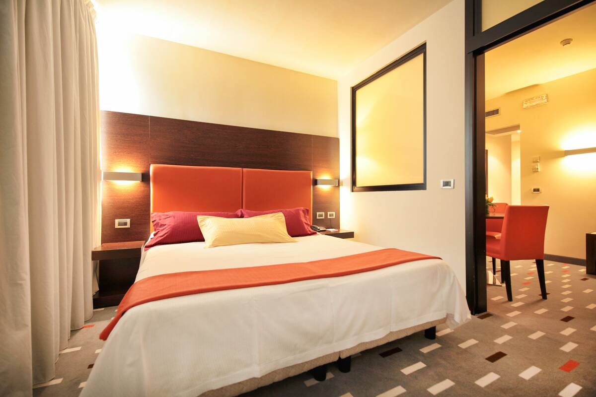 Una habitación de hotel con una cama grande, un cabecero de madera y un escritorio con una silla.