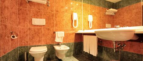 A modern bathroom with a bidet, toilet, sink, and towel rack.