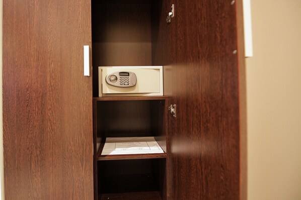 A wooden wardrobe with a microwave on the top shelf.