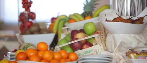 Una mesa de buffet con diversas frutas y verduras, como naranjas, manzanas y plátanos.