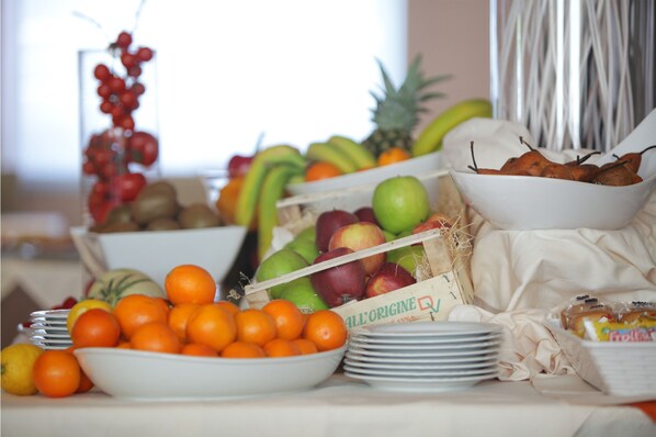 A buffet table with various fruits and vegetables, including oranges, apples, and bananas. - Hotel Major (Ronchi dei Legionari)