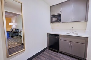 Ein kompaktes Hotelzimmer mit Küchenzeile, einer Mikrowelle, einem Spülbecken und einem kleinen Kühlschrank.