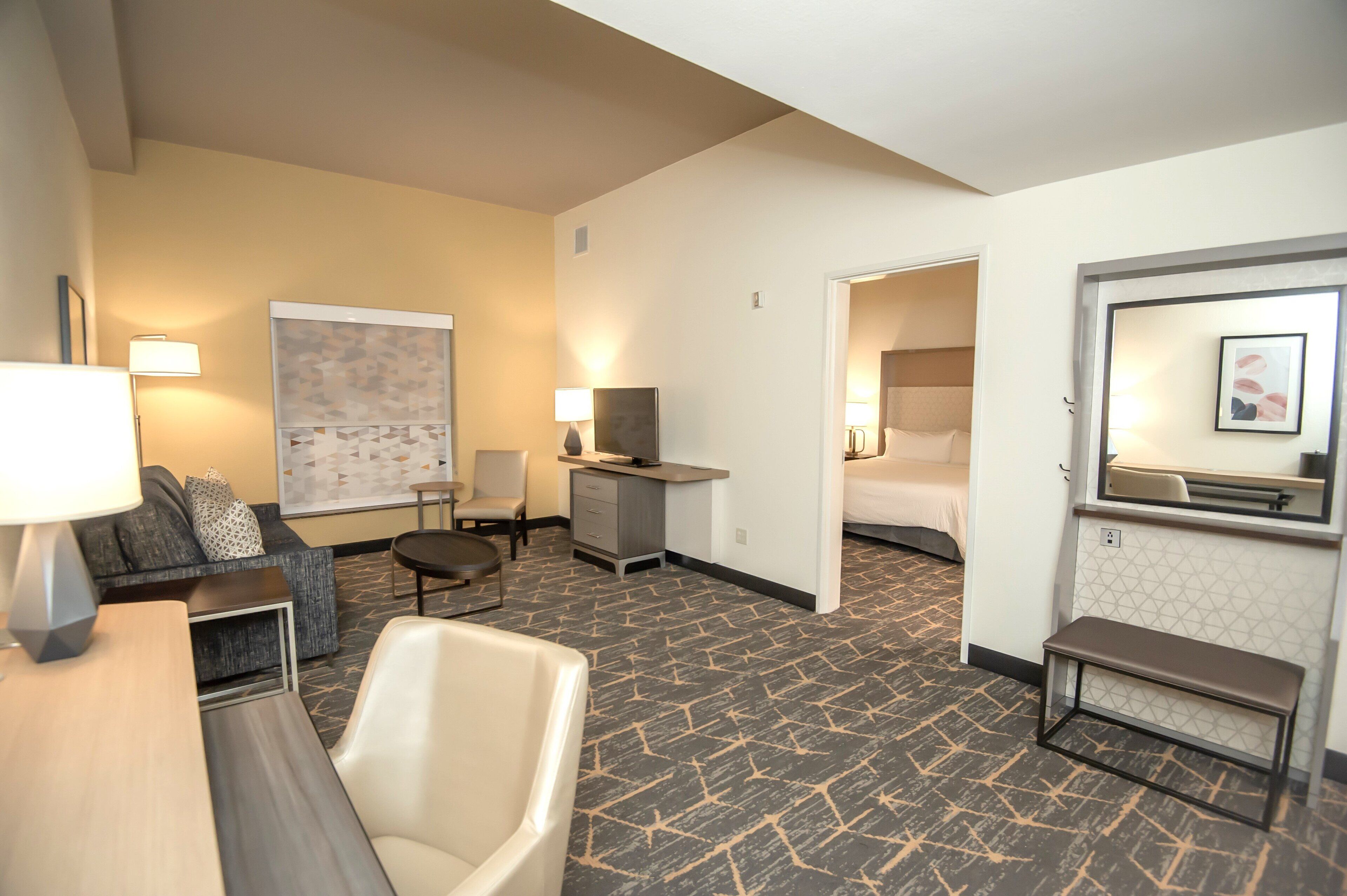 Una habitación de hotel con sofá, sillón, escritorio y cama.