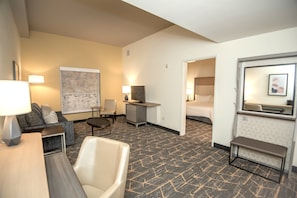 Una habitación de hotel con sofá, sillón, escritorio y cama.
