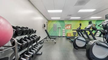 A gym with exercise equipment including dumbbells, a stationary bike, and treadmills.