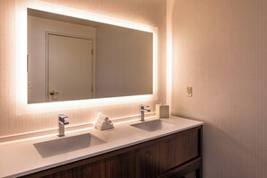 Ein Badezimmer mit zwei Waschbecken, einem großen Spiegel und einer hölzernen Waschtischablage.