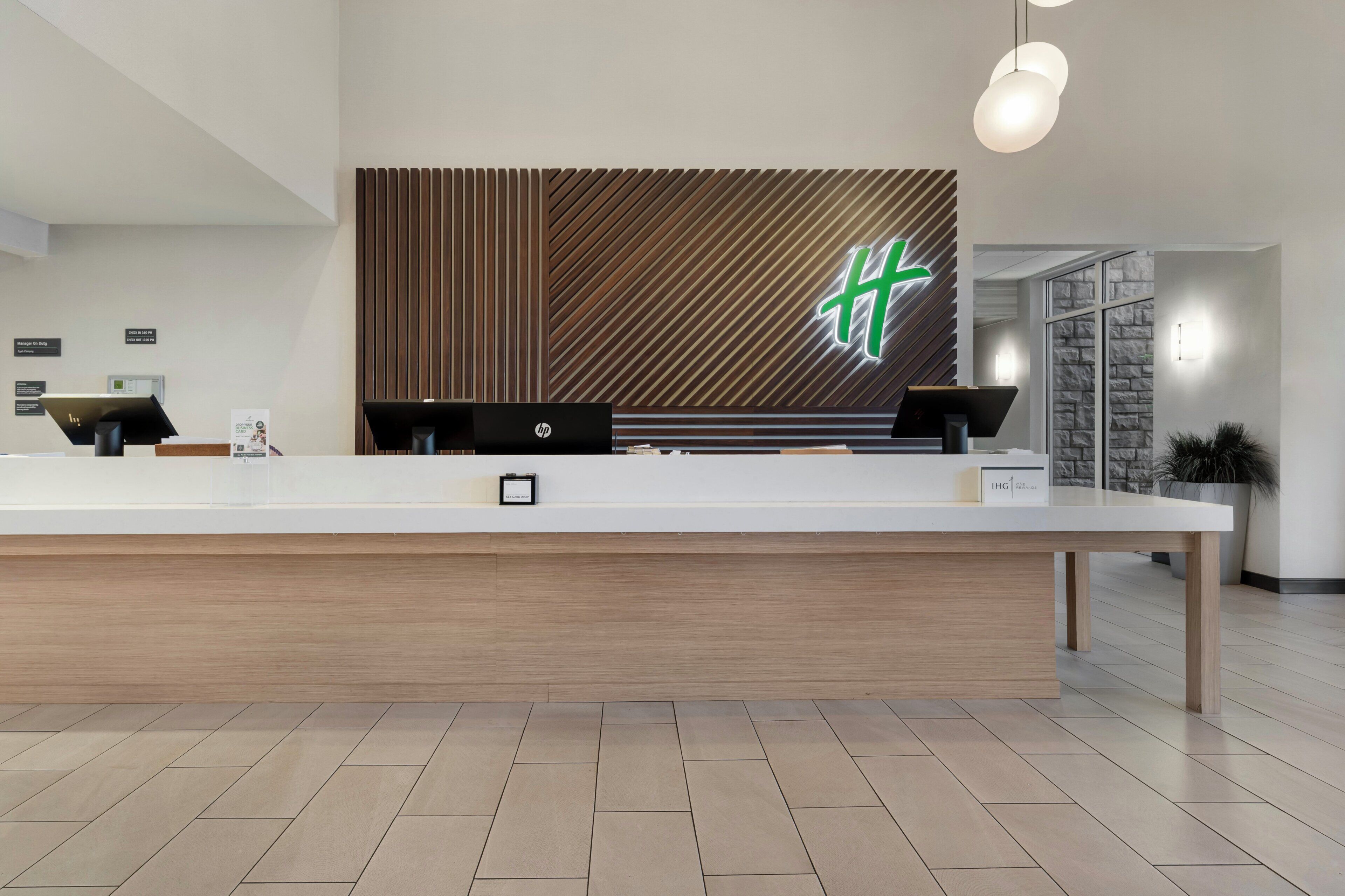 A reception desk with a modern design, a wooden panel wall, and a logo.