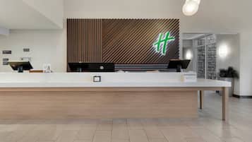 A reception desk with a modern design, a wooden panel wall, and a logo.