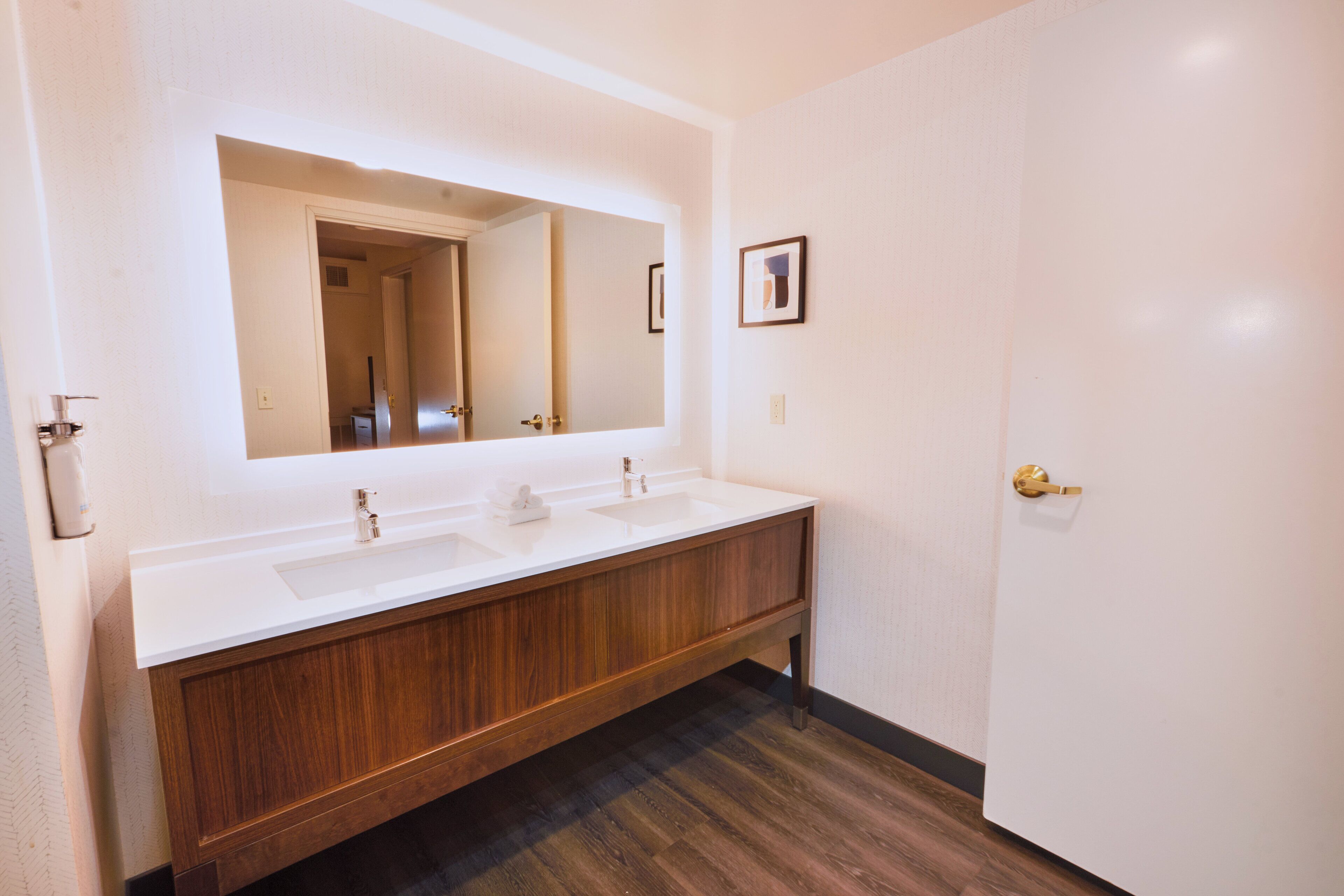 A bathroom with a wooden vanity, a large mirror, and a white sink.
