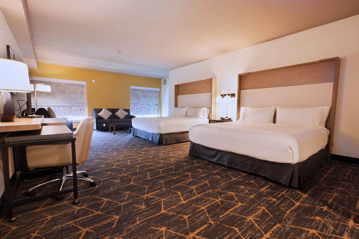 A hotel room with two beds, a desk, and a chair.