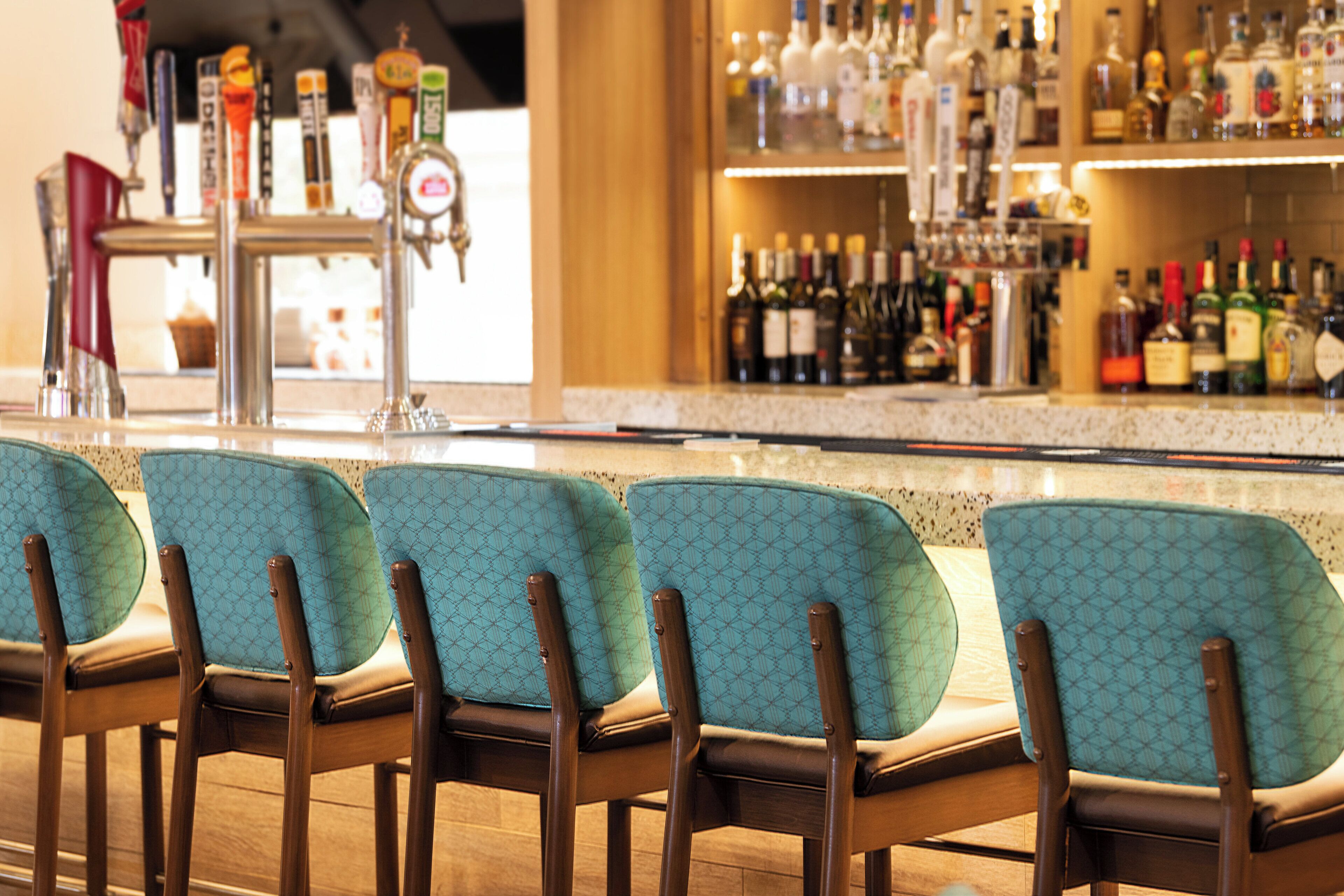 A bar area with multiple chairs and a variety of bottles in the background.
