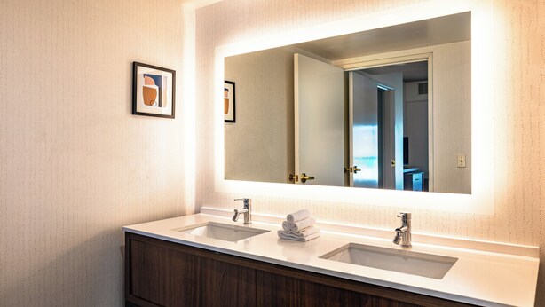 A bathroom with two sinks, a large mirror, and a framed picture on the wall. - Holiday Inn & Suites Oakland Airport by IHG (Oakland)