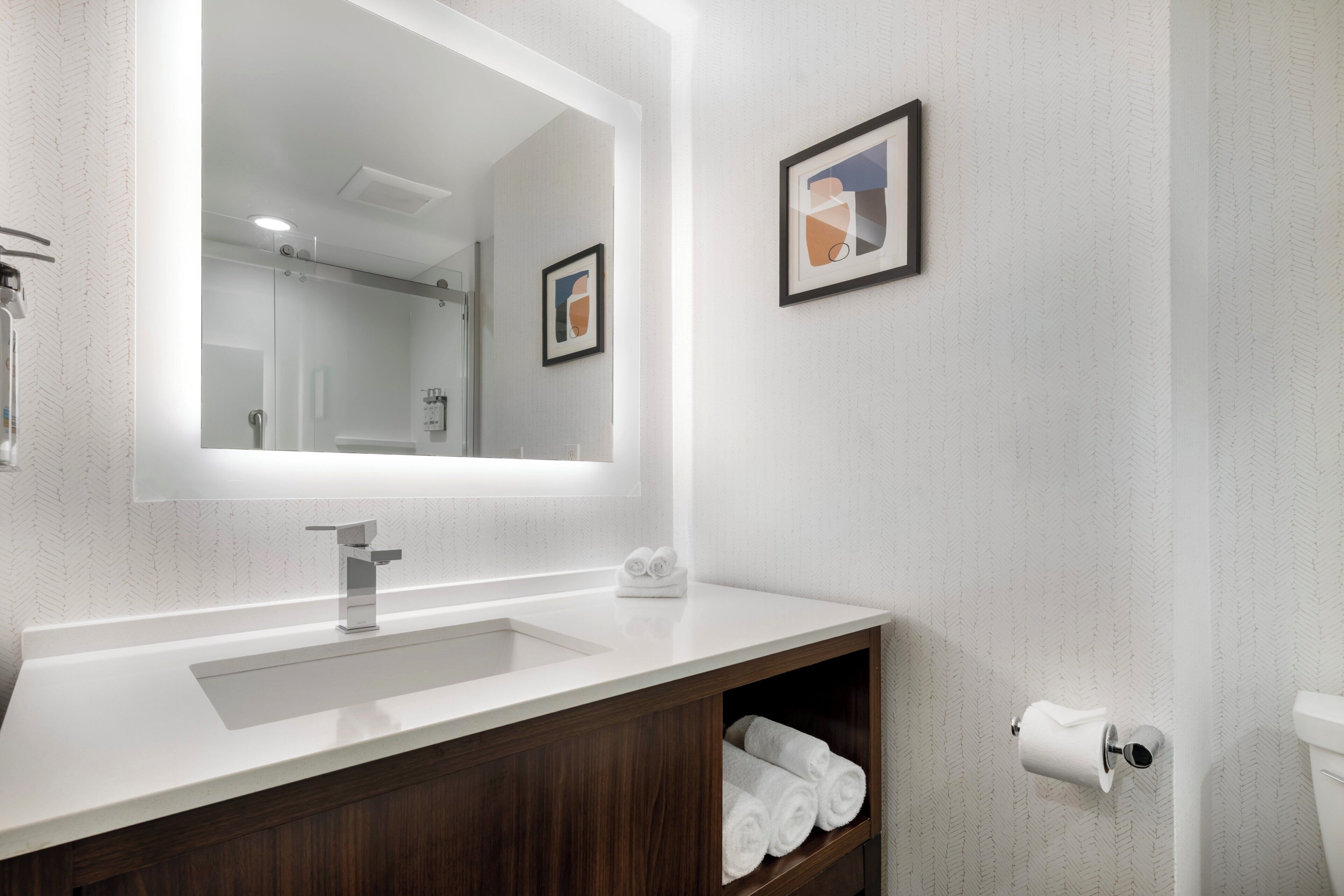 Une salle de bain avec un grand miroir, un lavabo, des toilettes et un porte-serviettes.