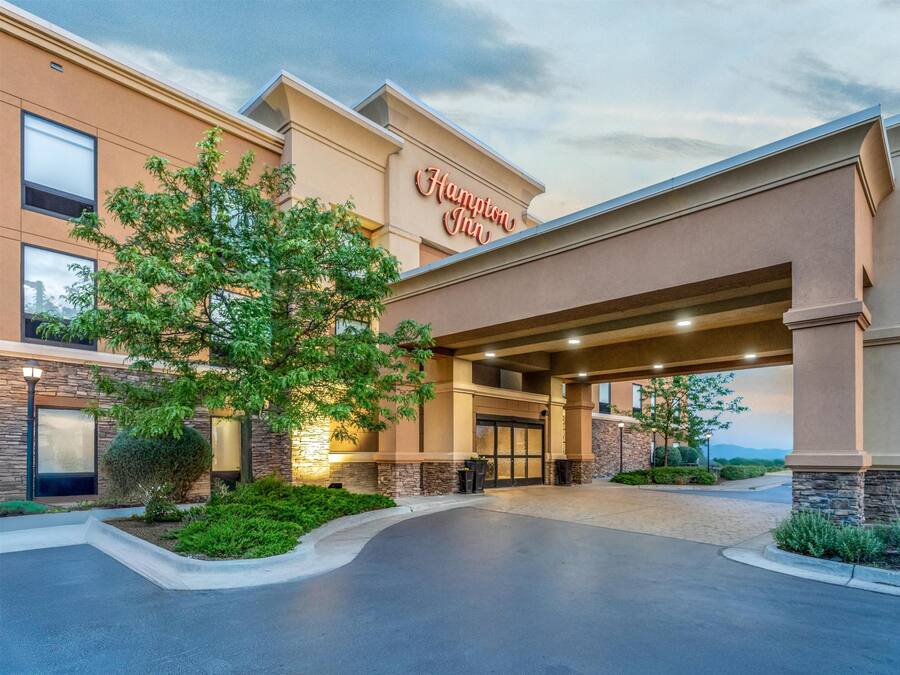 A Hampton Inn hotel entrance with a modern design, featuring a large overhang, stone accents, and a welcoming entrance.