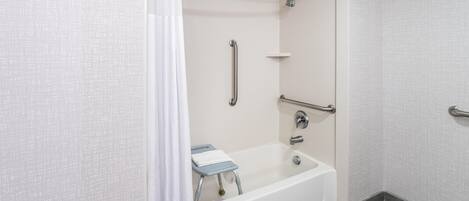 A modern bathroom with a walk-in shower, grab bars, and a wheelchair-accessible bench.
