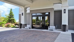 A modern hotel entrance with a covered walkway, large glass doors, and outdoor seating. - Hampton Inn & Suites Salt Lake City-West Jordan (West Jordan)