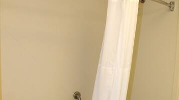 A shower with a white curtain, a grab bar, and a towel rack.