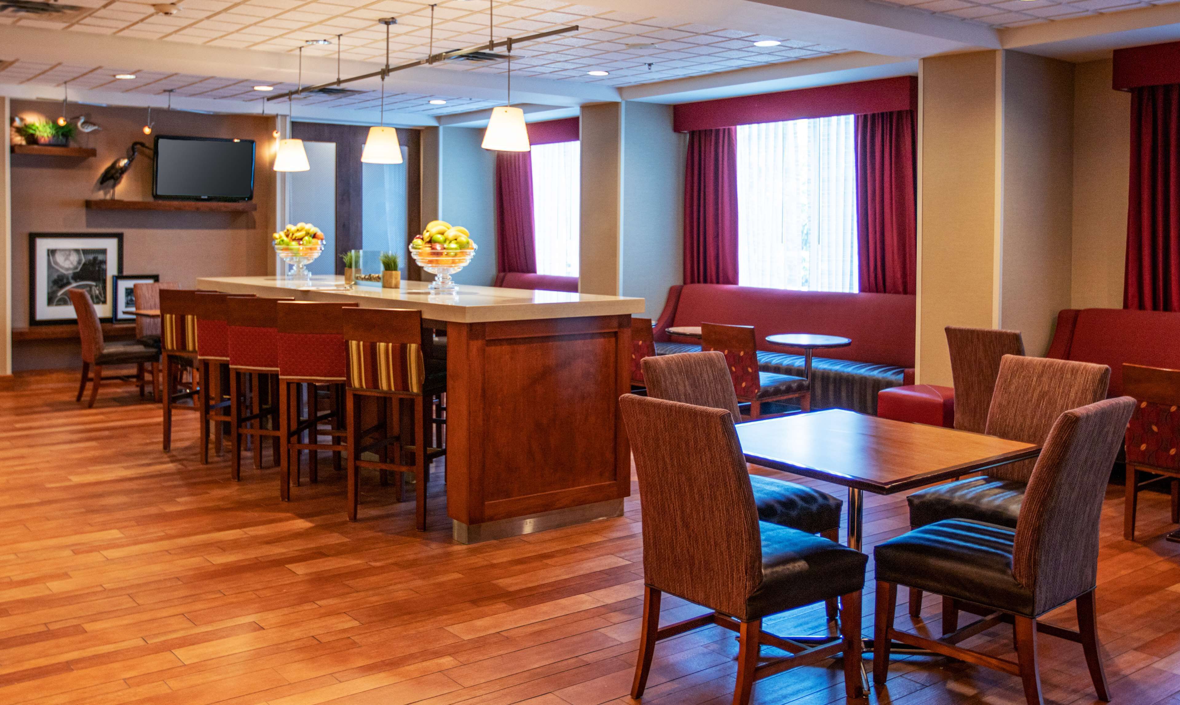 A hotel lobby with a bar area, seating arrangements, and a television mounted on the wall.