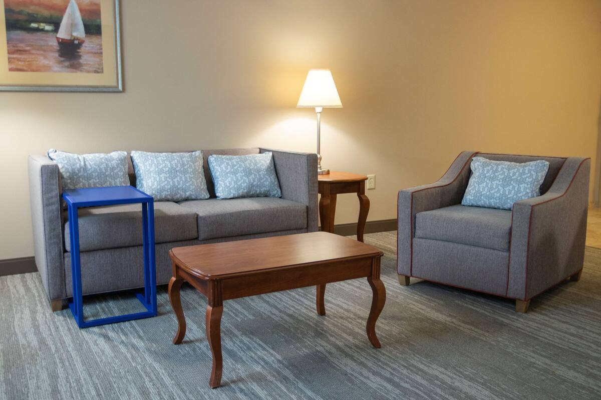 A living room with a sofa, armchair, coffee table, and a lamp.