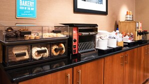 A bakery counter with various baked goods, a coffee machine, and a sign indicating a daily item.