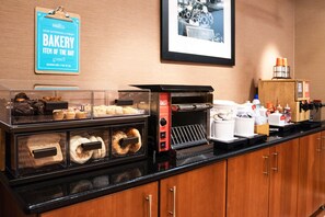 A bakery counter with various baked goods, a coffee machine, and a sign indicating a daily item.