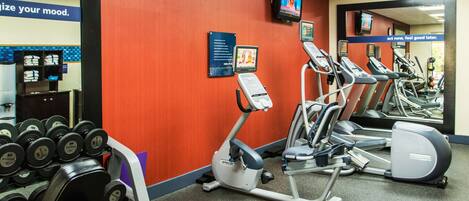 Ein Fitnessstudio mit Laufbändern, Crosstrainern und Kurzhanteln.