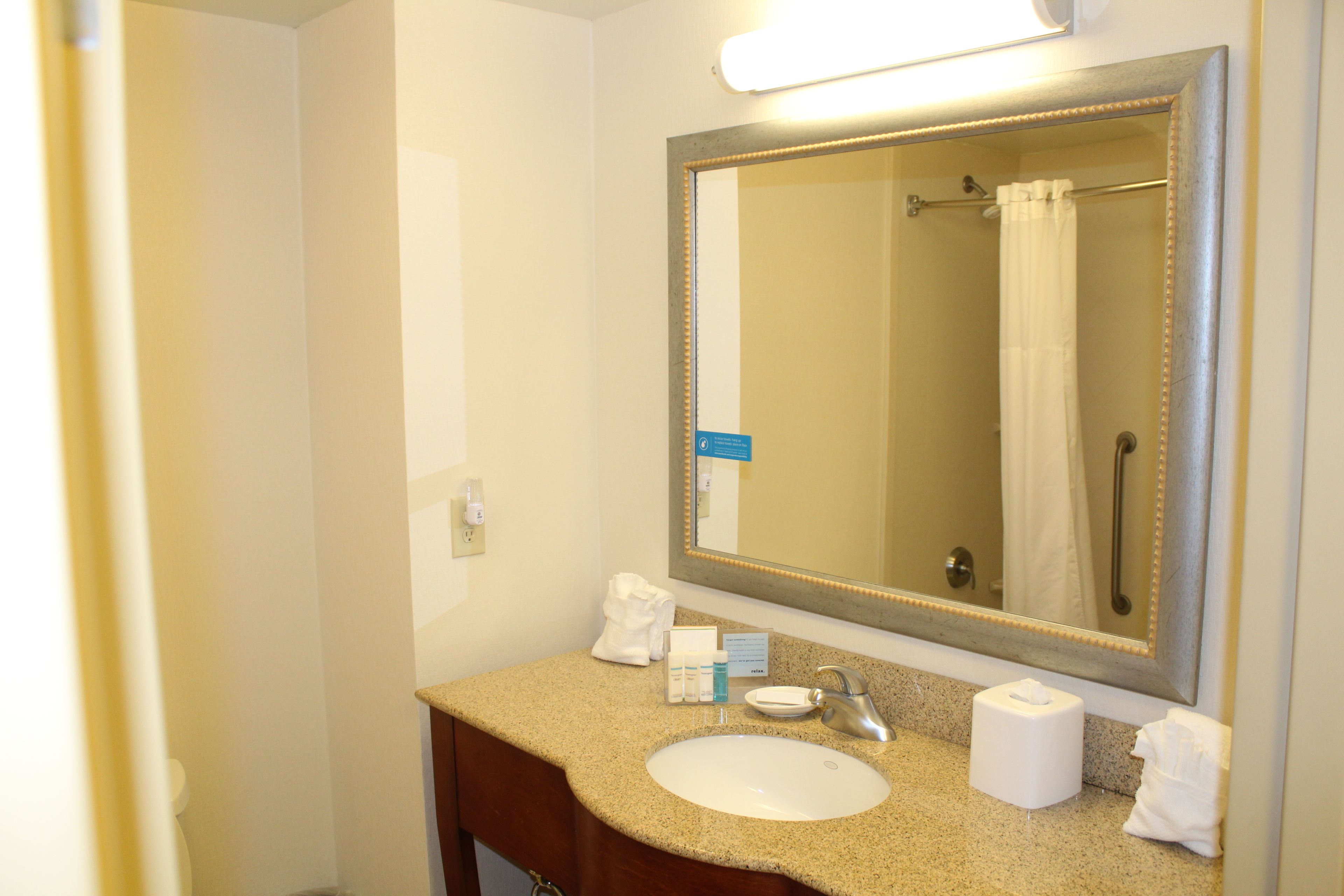 A bathroom with a sink, mirror, and towel rack.