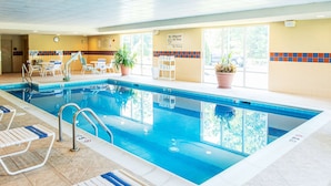 An indoor swimming pool with clear water, lounge chairs, and potted plants. - Hampton Inn Gloucester (Gloucester)