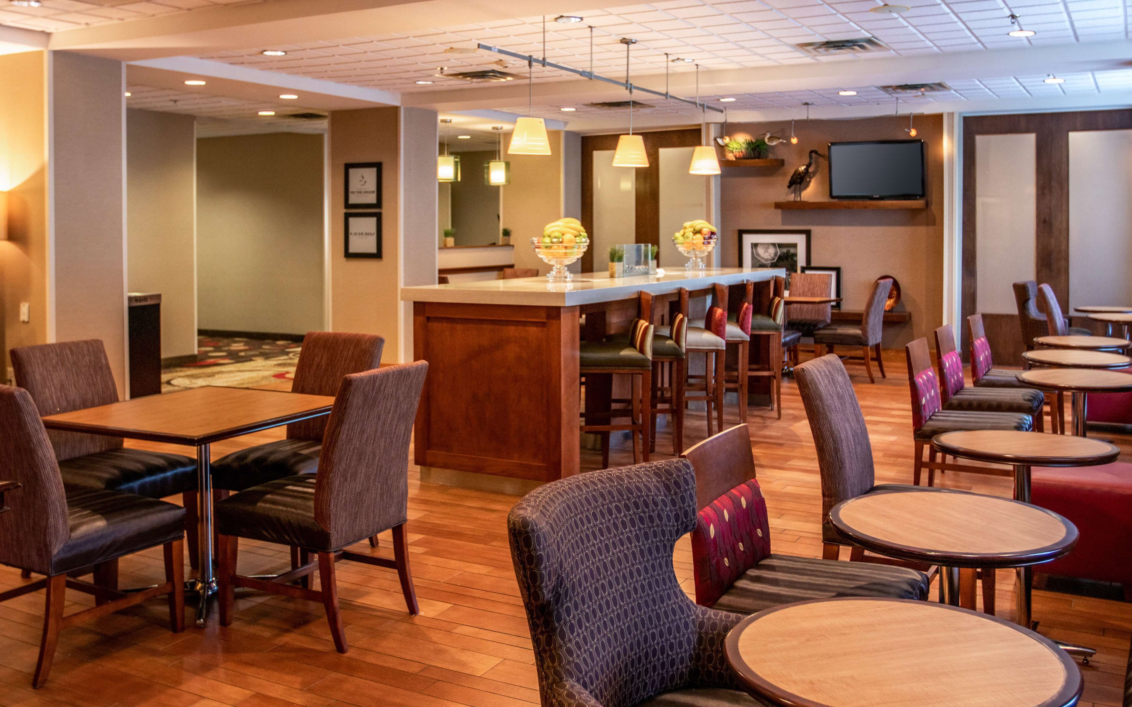A hotel lobby with a bar area, seating arrangements, and a television mounted on the wall.