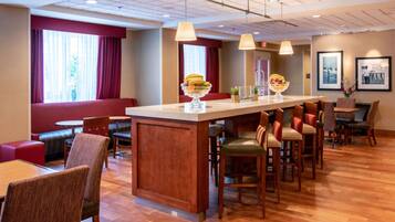 A hotel lobby with a bar area, seating arrangements, and framed pictures on the walls.