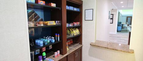 A kitchenette with shelves stocked with snacks, beverages, and cleaning supplies.