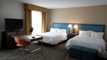 A hotel room with a bed, a desk, a chair, a TV, and a lamp.