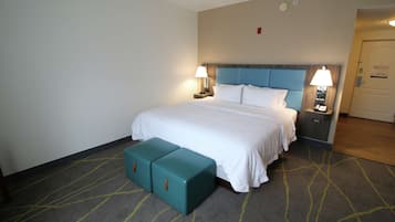 Una habitación de hotel con una cama, dos mesitas de noche y un banco.