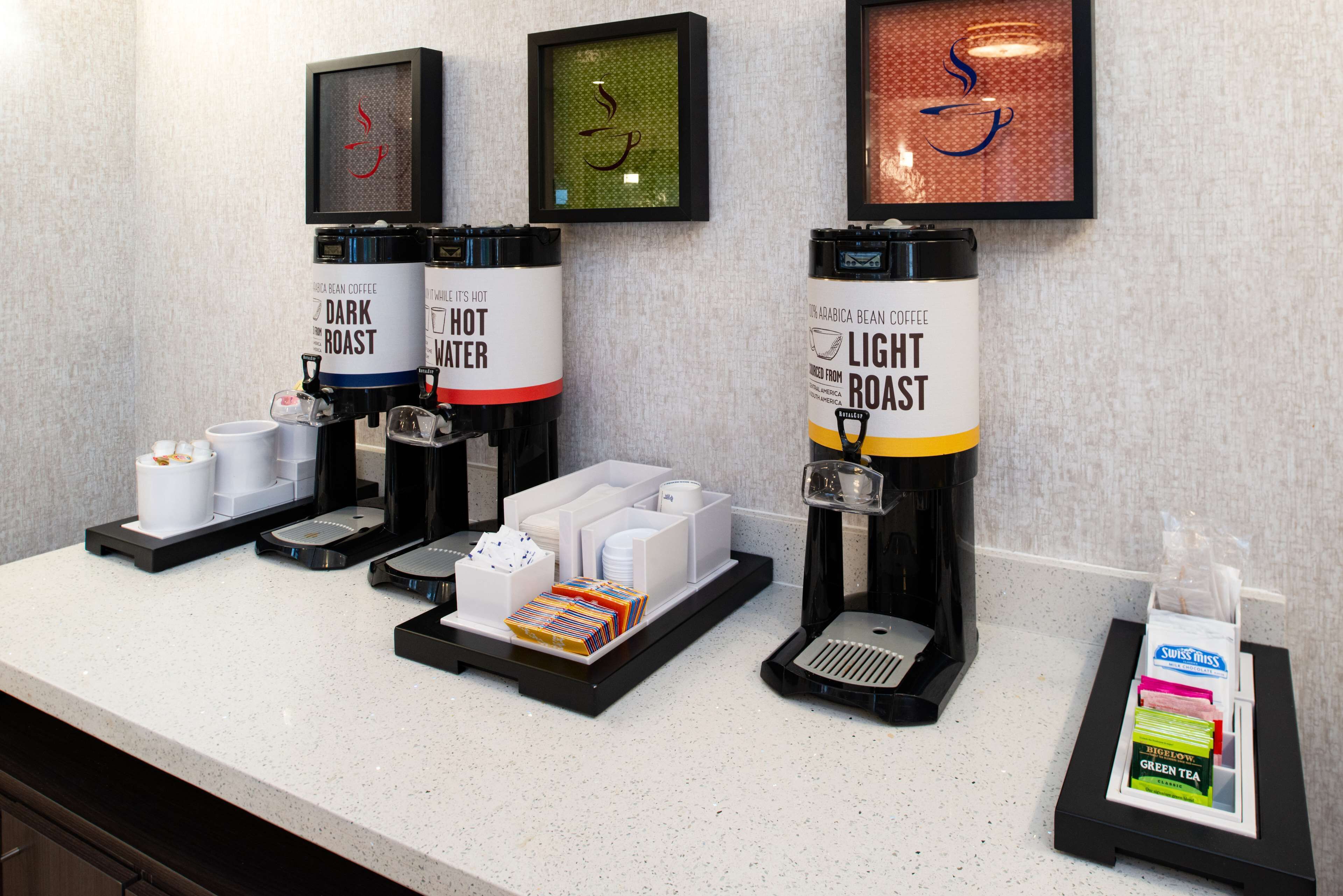 A coffee station with two coffee dispensers labeled "Dark Roast" and "Light Roast," along with a water dispenser and a tea dispenser.