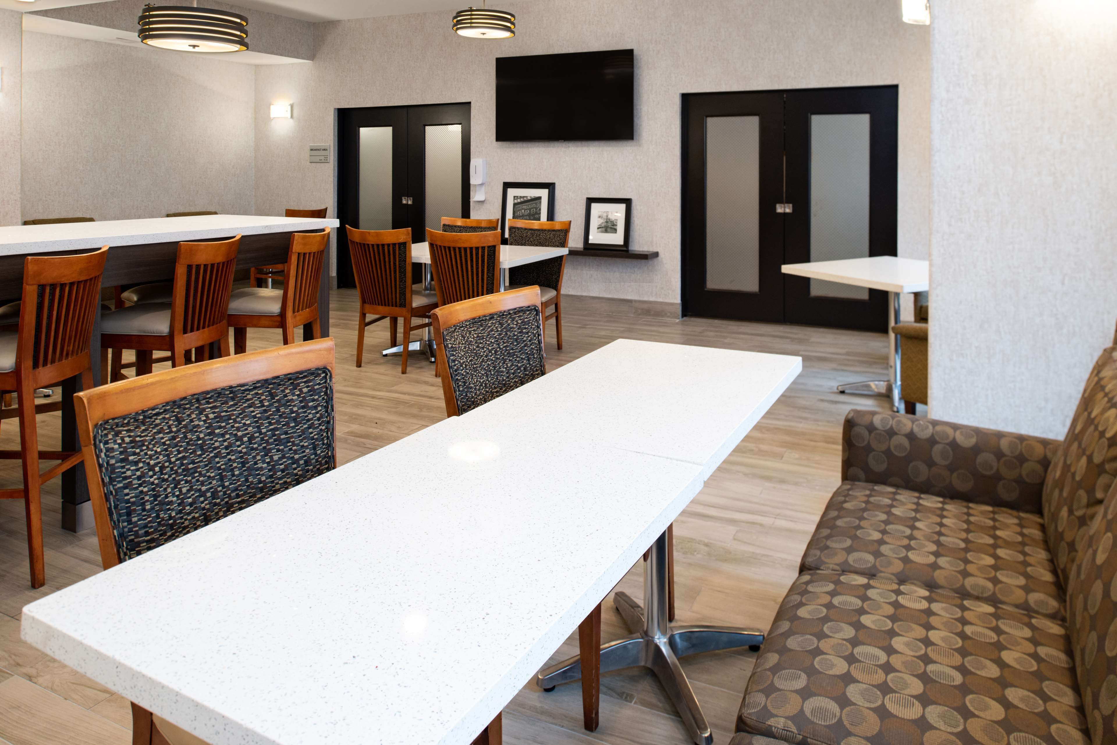 A modern dining area with a long table, several chairs, and a sofa.