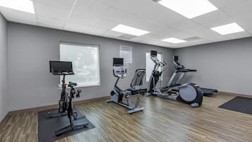 A fitness room with exercise equipment, a large window, and a sign detailing equipment rules.