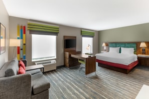 Habitación de hotel con cama, escritorio, silla y televisor.