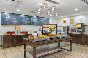 A breakfast area with a buffet table, a juice station, and a chalkboard menu.