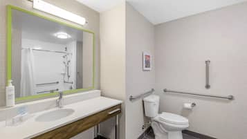 A modern bathroom with a sink, mirror, toilet, and grab bars.
