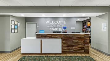 A reception desk with a 'WELCOME TO THE PEACH STATE' sign, framed certificates on the wall, and a 'Hilton Honors' sign.