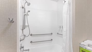 A shower with a handheld showerhead, grab bars, and a non-slip floor.