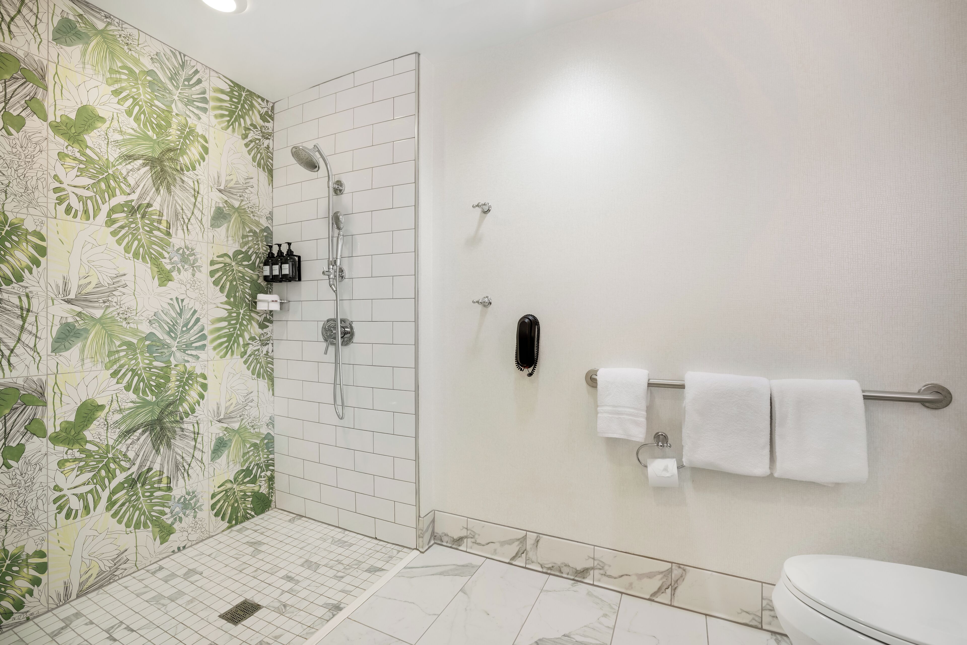 Une salle de bain équipée d’une douche, de toilettes et d’un porte-serviettes.